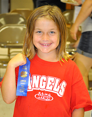 4-H youth displaying county fair ribbon