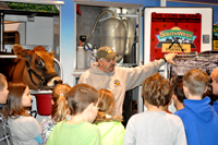 Dairy farmer and dairy cow with schoold children