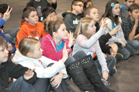 Students sitting on floor with hands raised